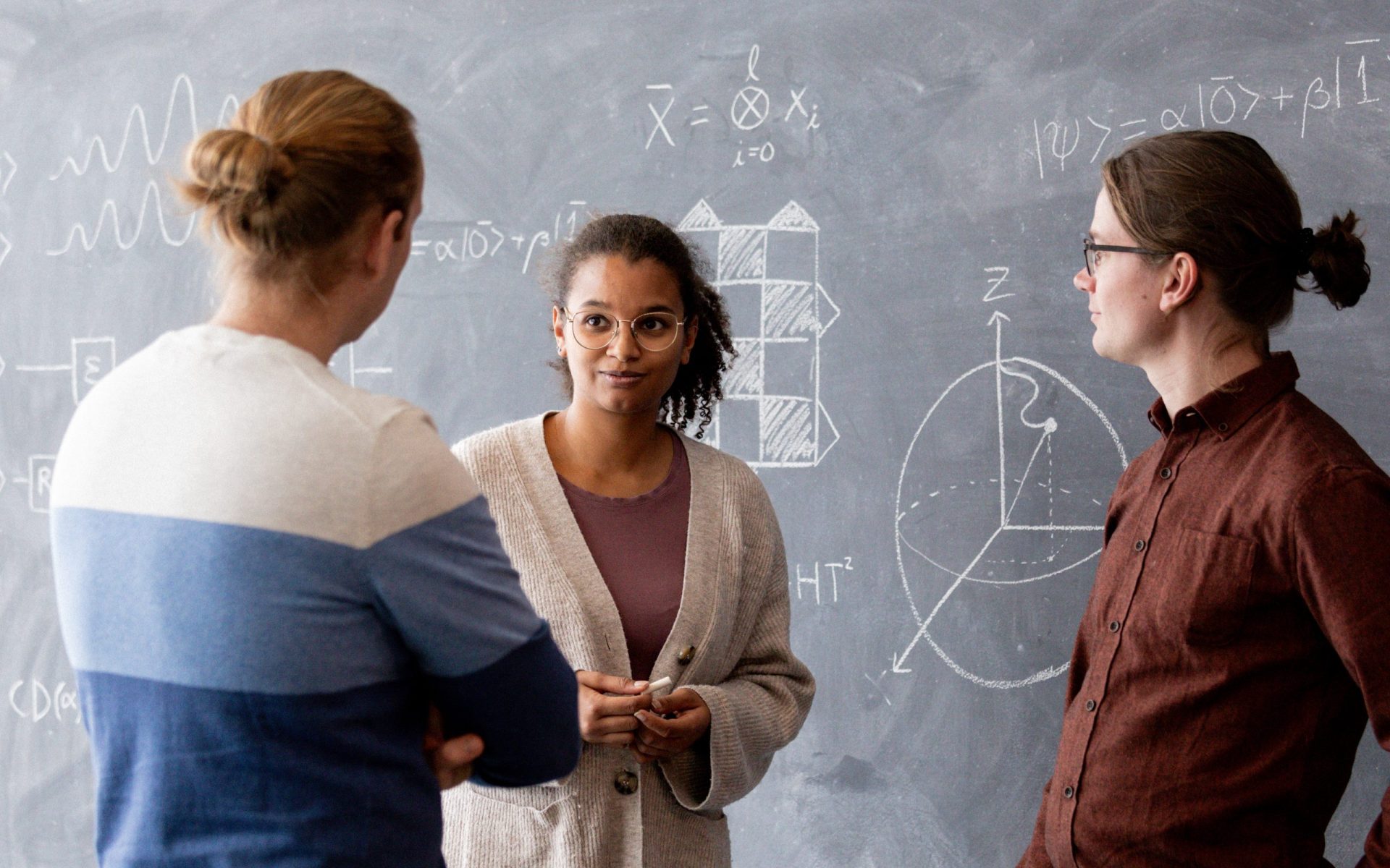 Three people working near a blackboard at Nord Quantique